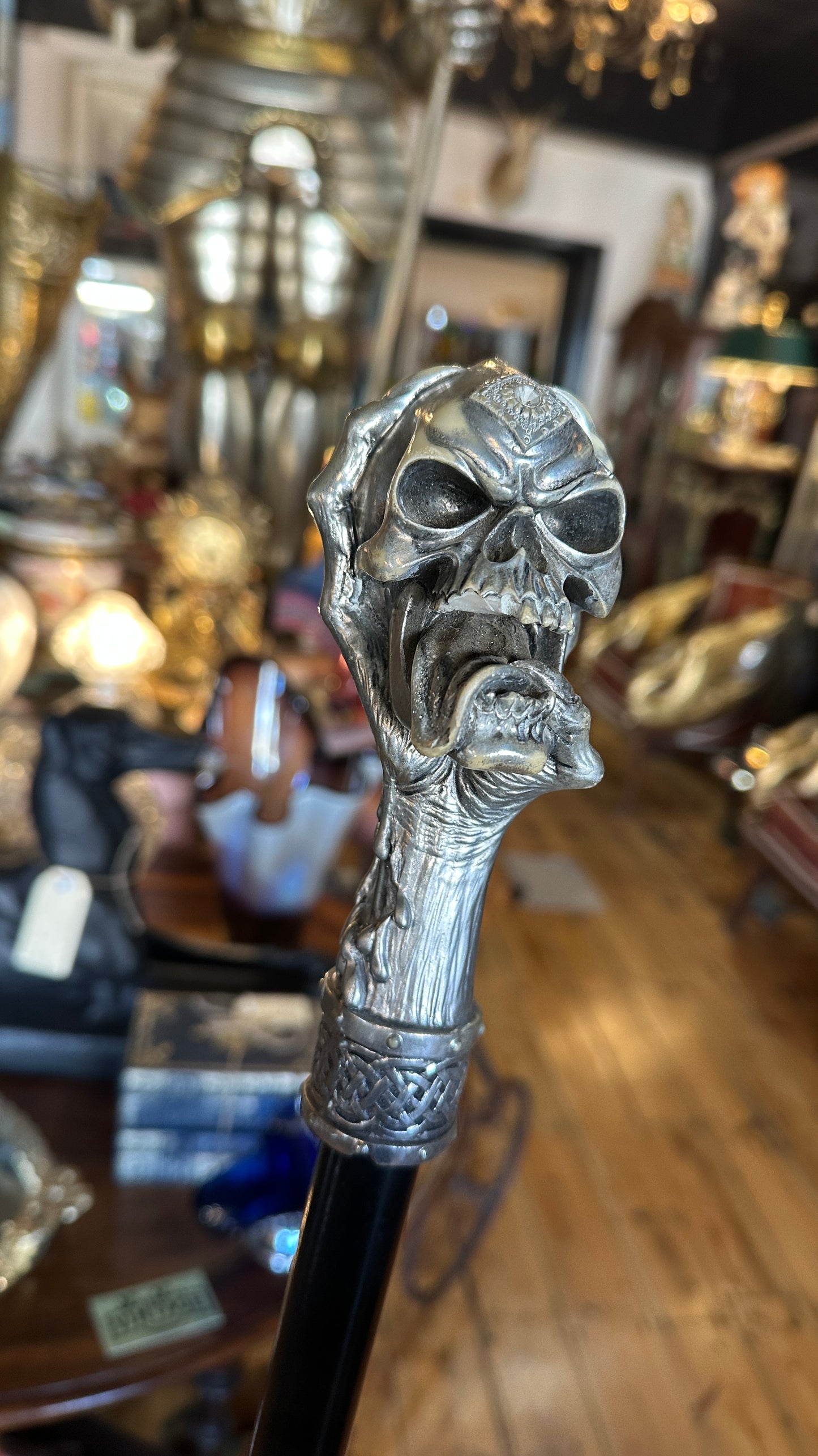 Walking cane/ stick featuring a gothic style silver-colored skull handle mounted on a black shaft