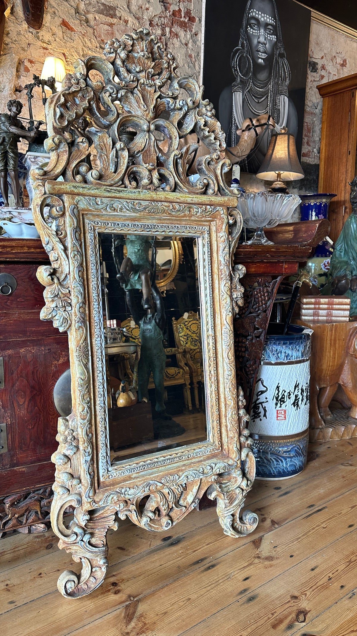 Ornate wall mirror featuring a distressed or painted finish in a Baroque or Rococo style