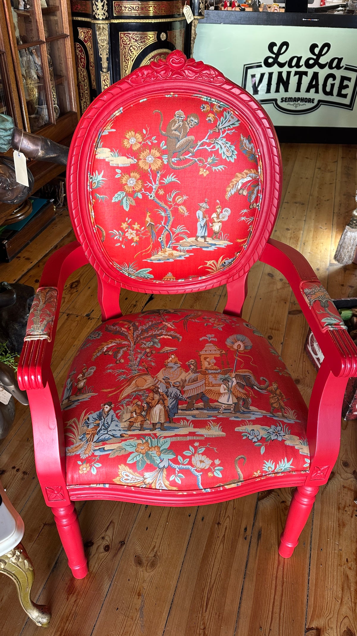 Striking Louis XVI-style armchair exquisitely upholstered in a red Chinoiserie garden scene motif