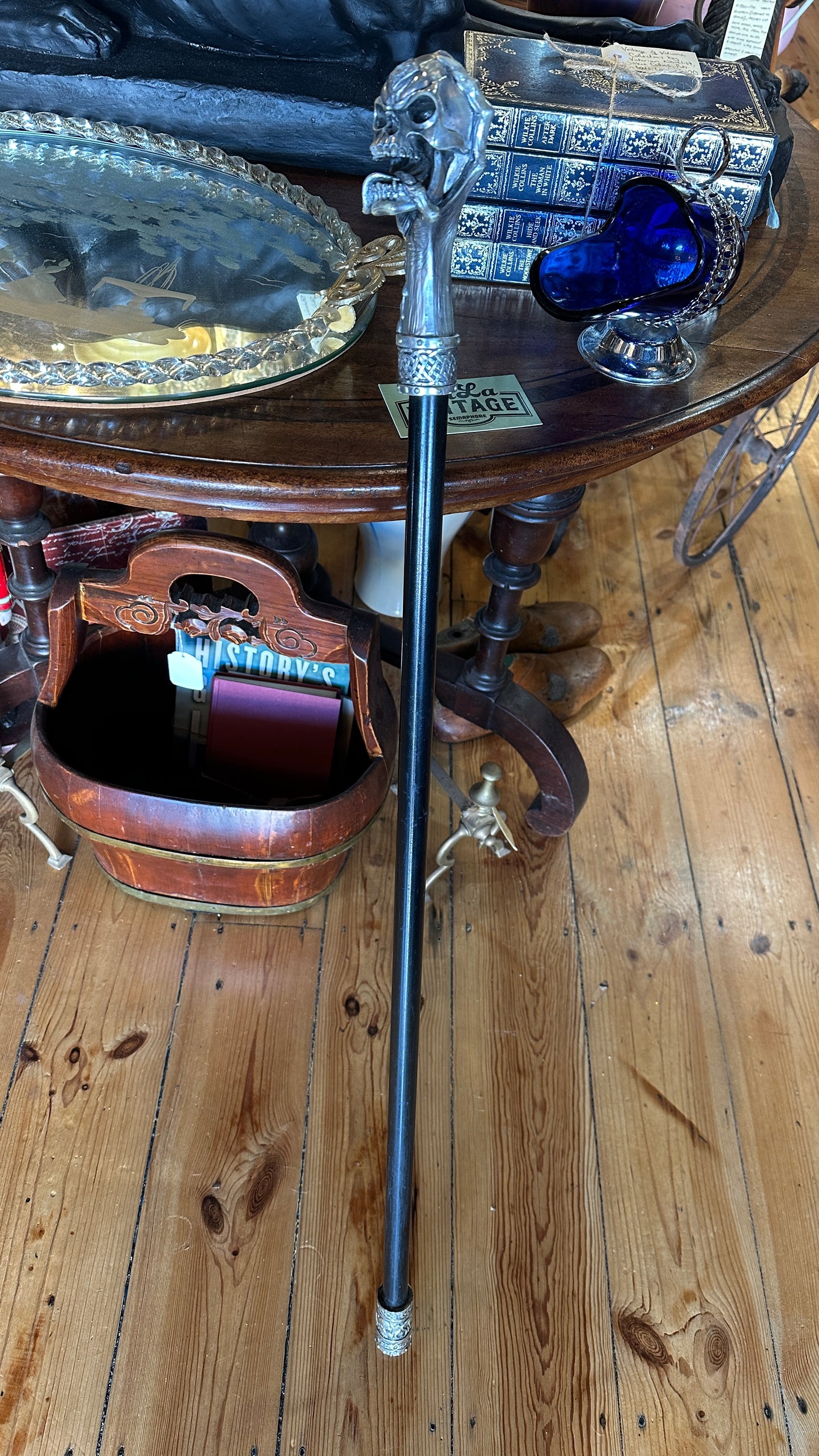 Walking cane/ stick featuring a gothic style silver-colored skull handle mounted on a black shaft