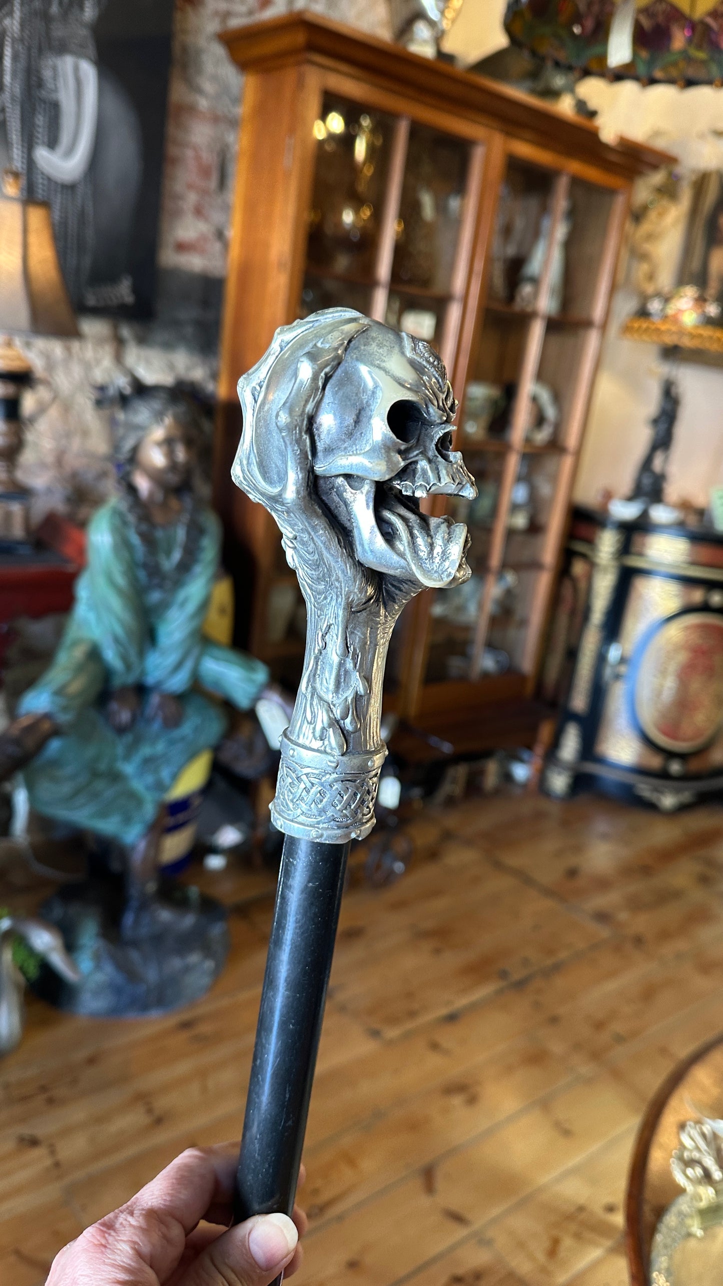 Walking cane/ stick featuring a gothic style silver-colored skull handle mounted on a black shaft