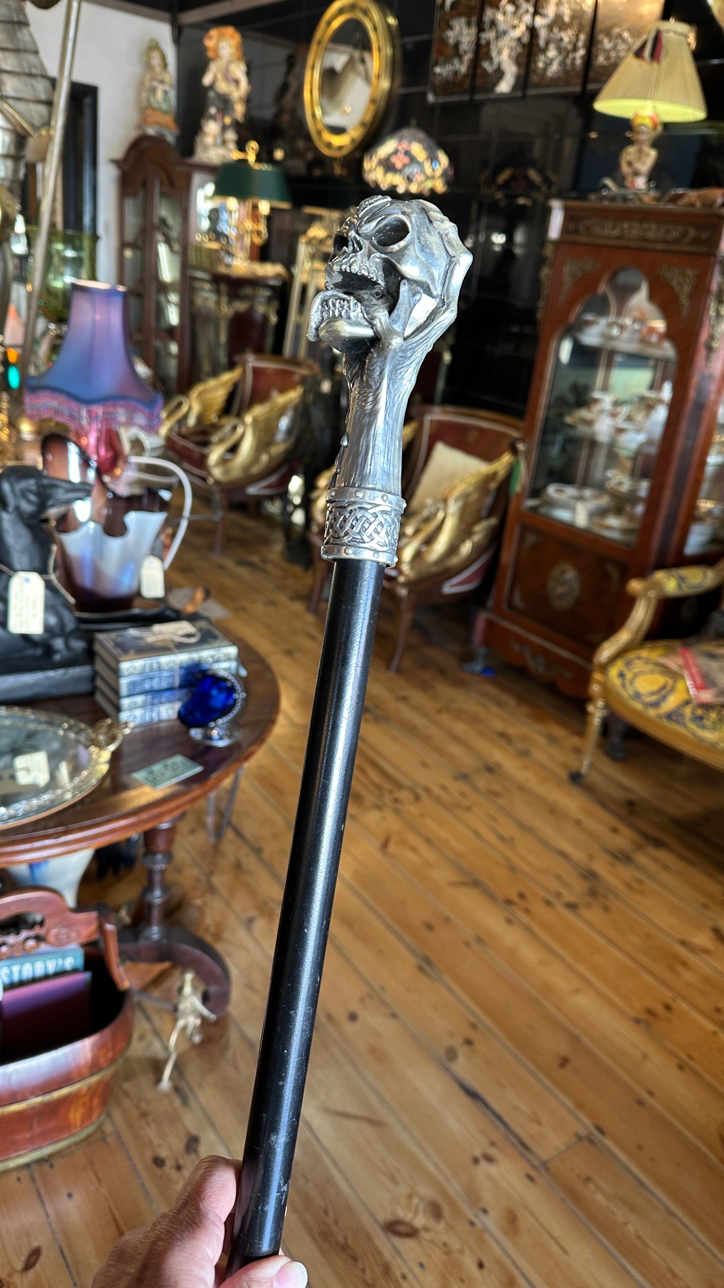 Walking cane/ stick featuring a gothic style silver-colored skull handle mounted on a black shaft