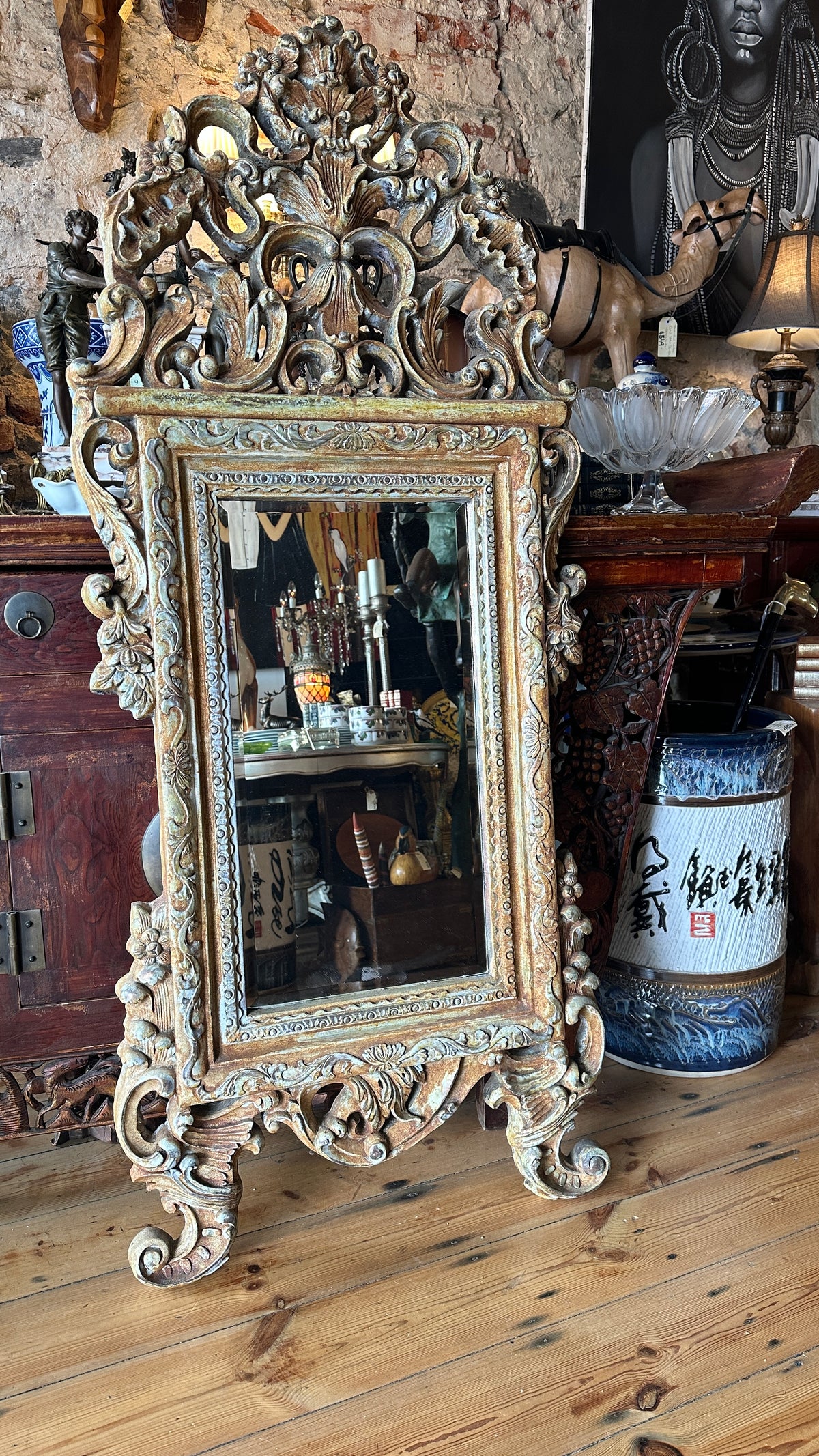 Ornate wall mirror featuring a distressed or painted finish in a Baroque or Rococo style