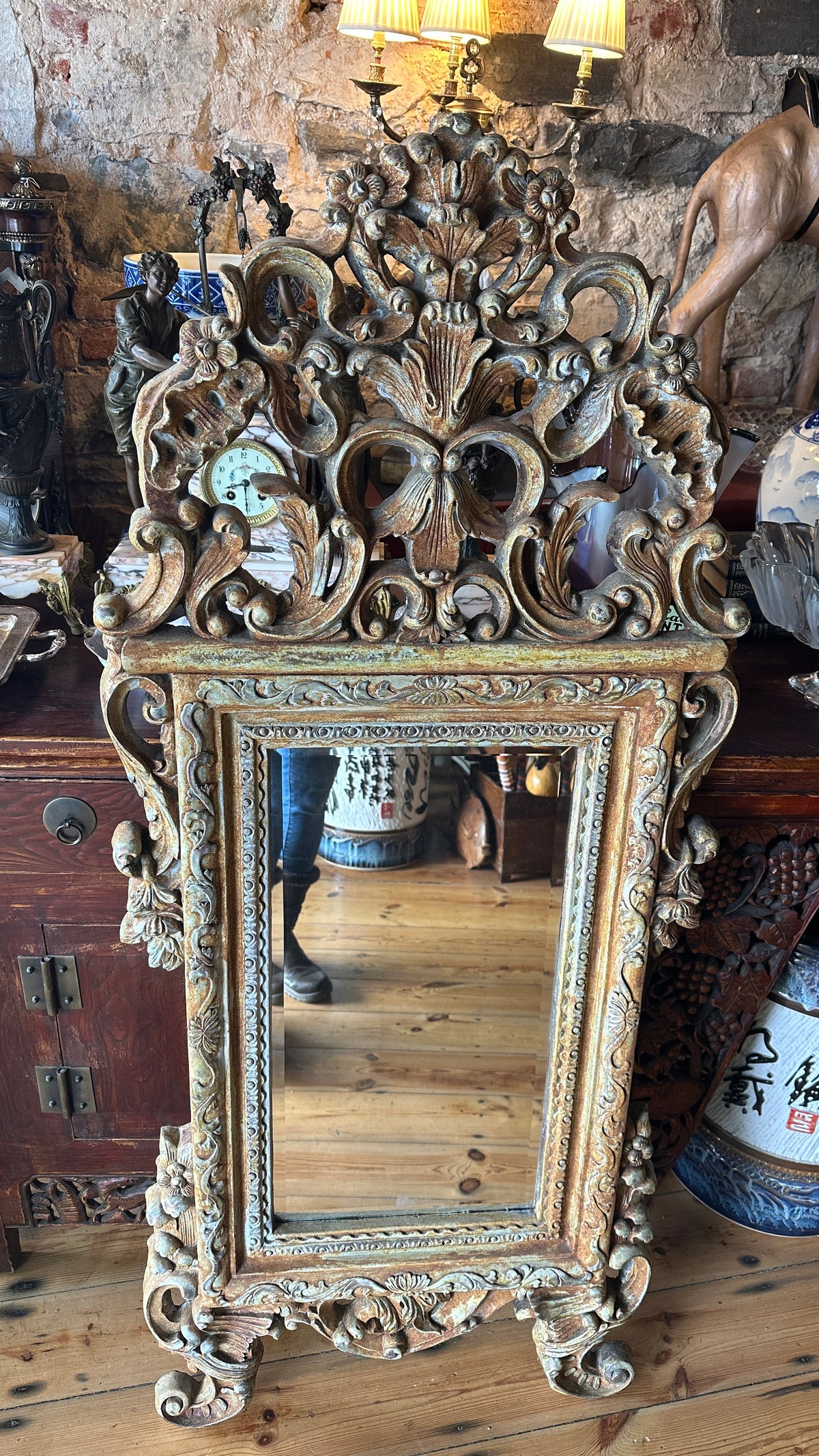 Ornate wall mirror featuring a distressed or painted finish in a Baroque or Rococo style
