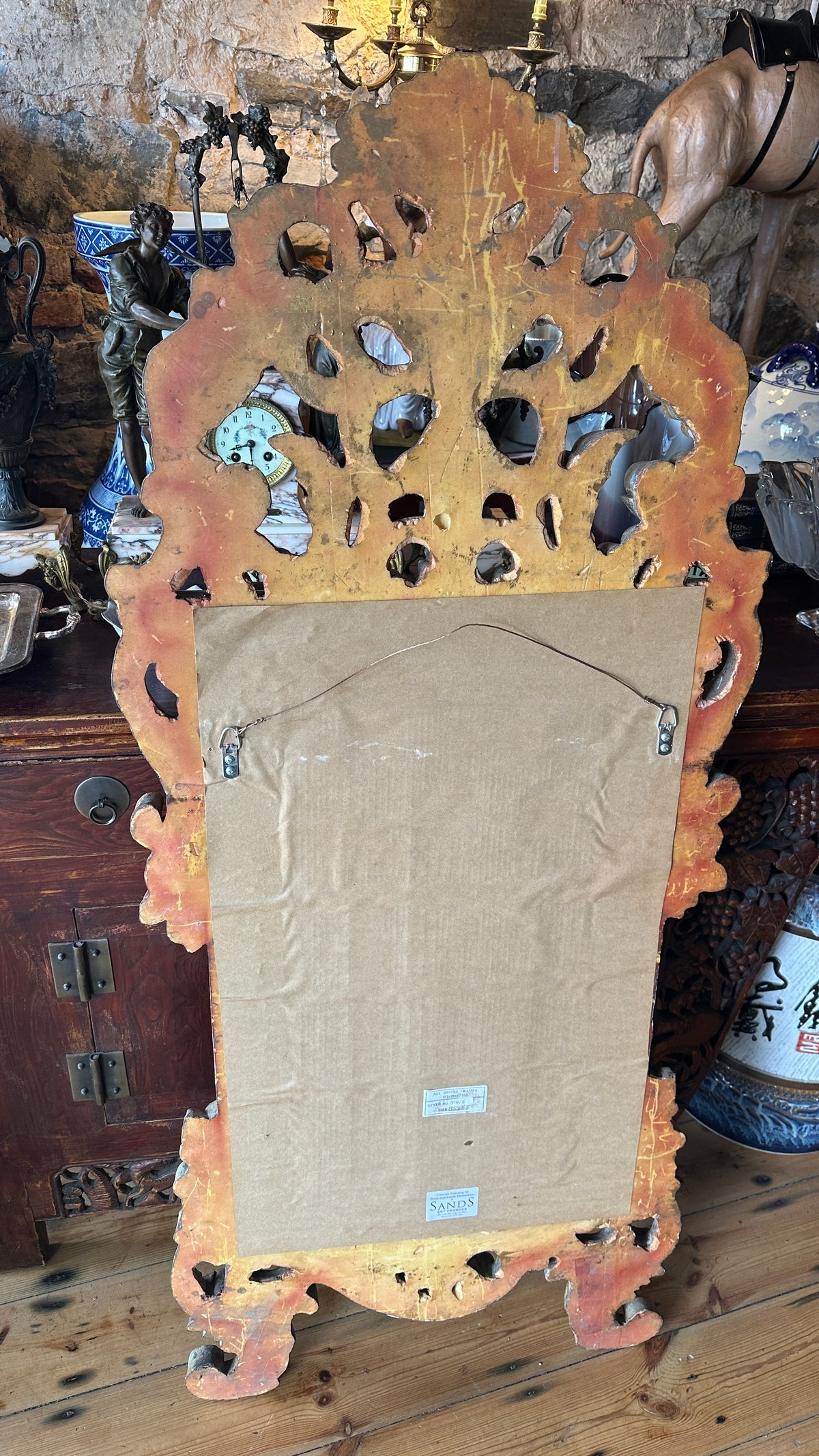 Ornate wall mirror featuring a distressed or painted finish in a Baroque or Rococo style