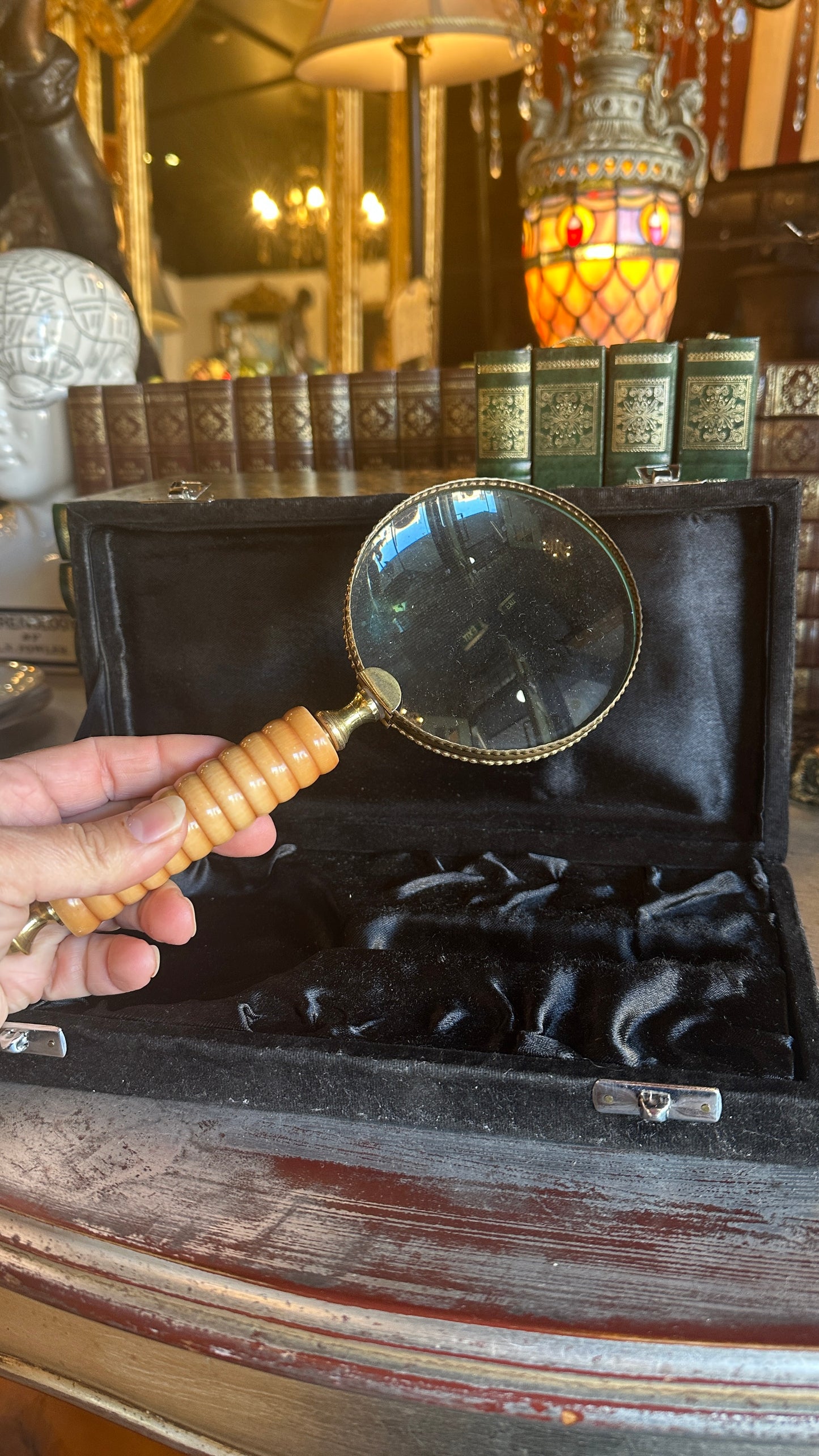 Vintage large brass and ribbed bone-style resin handle magnifying glass rests inside a black satin-lined presentation box